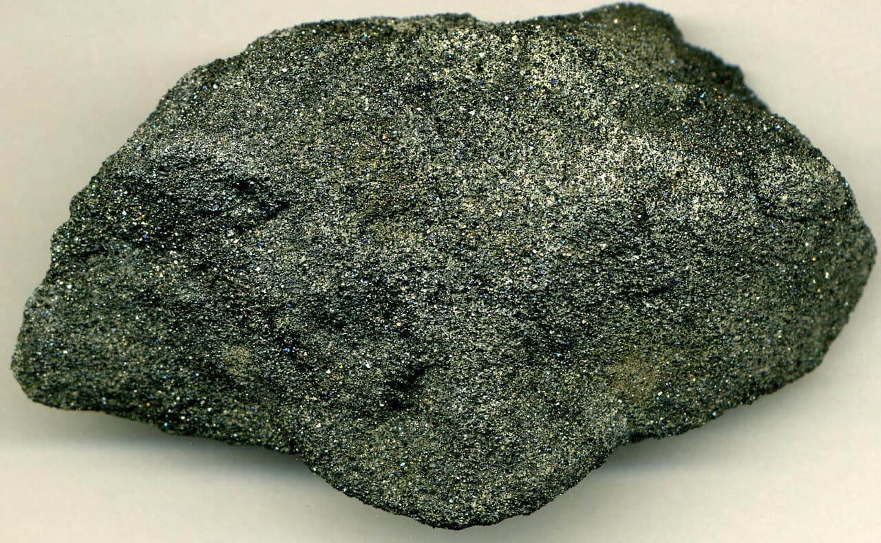 Cut slab of near-black, dense, fine-grained chromitite with a faint sub-horizontal layering.